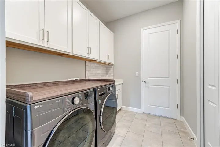 Large Laundry Room with built in cabinets featuring light tile patterned floors