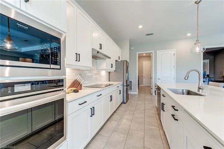 Kitchen with visible vents, under cabinet range hood, light countertops, stainless steel appliances, and a sink