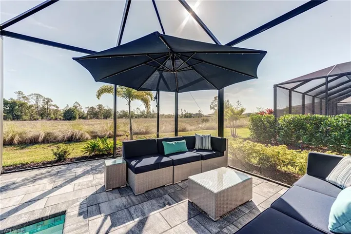 View of patio featuring screen enclosure and outdoor lounge area in this private preserve lot