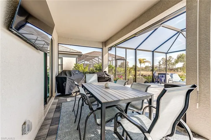 Another View of  this long patio / terrace featuring a lanai, a grill, and outdoor dining area
