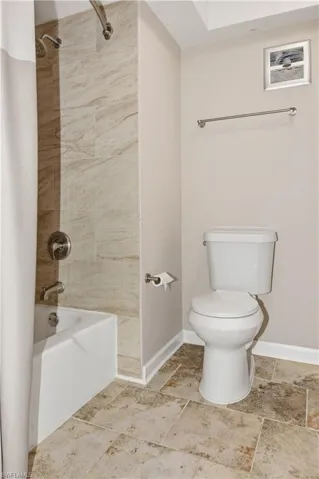 Full bathroom featuring shower / tub combo and light stone finish flooring