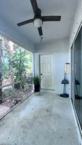 Covered patio featuring a ceiling fan with integrated lighting, concrete flooring, and an exterior door