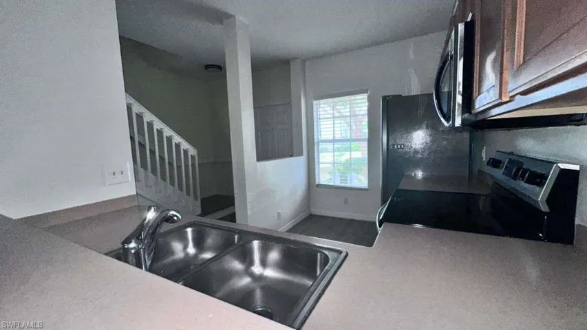 Kitchen featuring a double stainless steel sink, chrome faucet, laminate countertops, wood-finish cabinetry, and stainless steel appliances