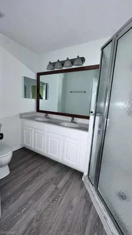 Bathroom featuring a double vanity with white cabinetry, a stone-finish countertop, and dual undermount sinks