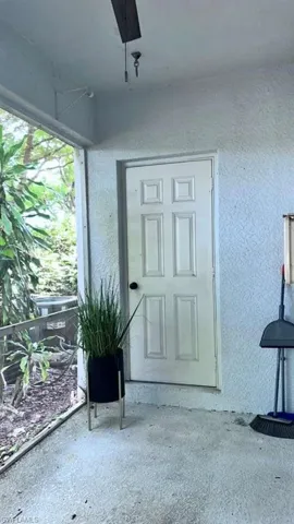 Screened outdoor area featuring a white paneled door, textured wall finishes, and a concrete-finish floor