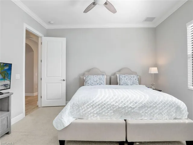 Bedroom with arched walkways, ornamental molding, a ceiling fan, and carpet floors