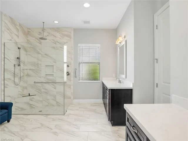 Bathroom with vanity, a shower stall, recessed lighting, and light marble finish floors
