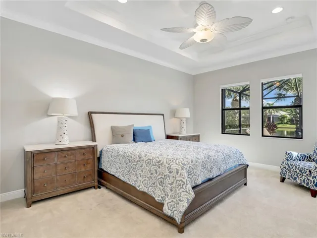 Carpeted bedroom with a tray ceiling, ornamental molding, a ceiling fan, and recessed lighting