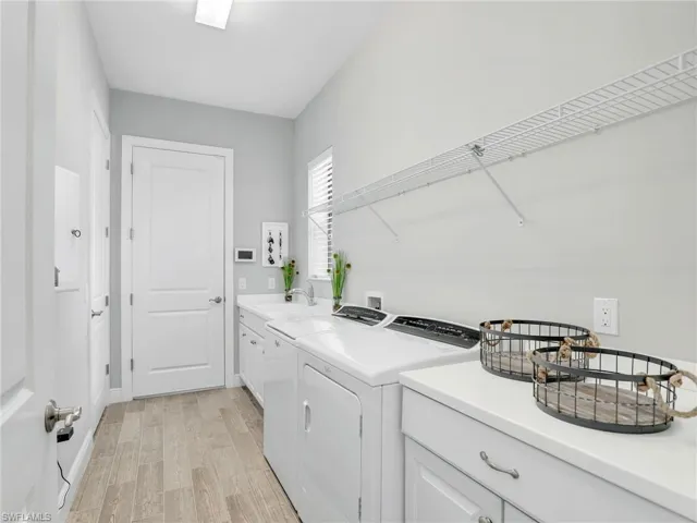 Laundry area featuring light wood-style floors, cabinet space, and washer and dryer