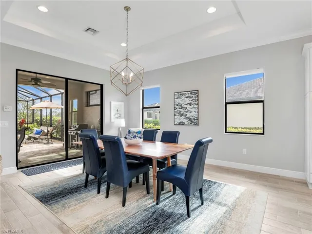 Dining room featuring a tray ceiling, light wood finished floors, plenty of natural light, recessed lighting, and crown molding
