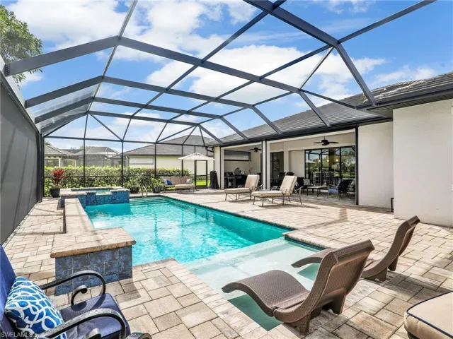 View of swimming pool with a ceiling fan, a pool with connected hot tub, a sunroom, a patio area, and glass enclosure