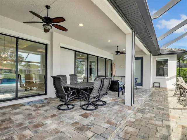 View of patio with outdoor dining space, ceiling fan, and glass enclosure