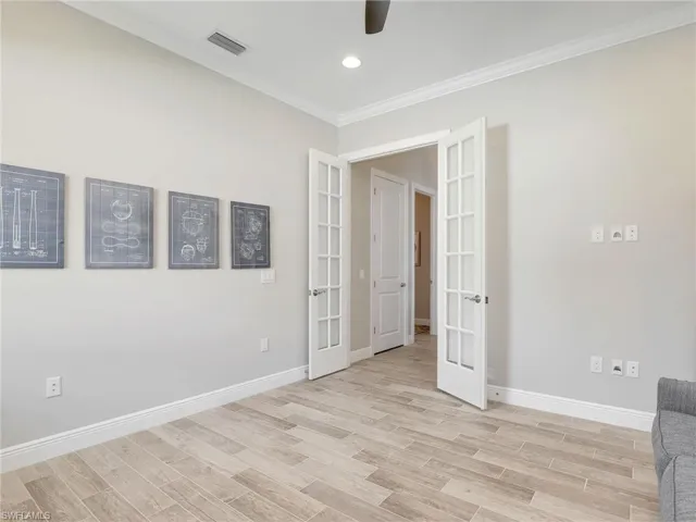 Empty room with french doors, crown molding, wood tiled floors, and recessed lighting