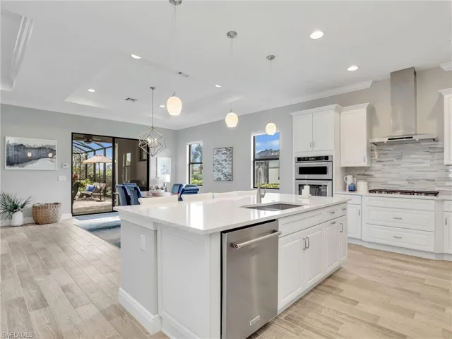 Kitchen with a tray ceiling, white cabinetry, recessed lighting, decorative backsplash, and appliances with stainless steel finishes