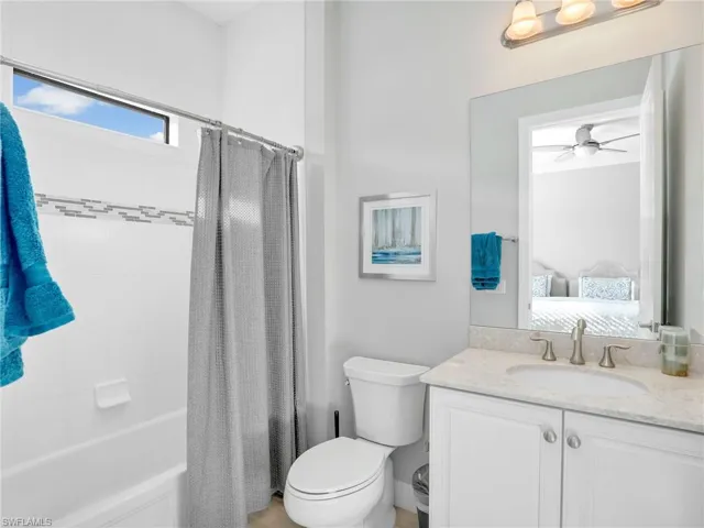 Ensuite bathroom featuring shower / bath combo, vanity, and a ceiling fan