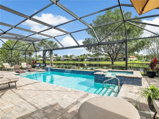 View of swimming pool featuring a sunroom, a water view, a patio area, a lanai, and a pool with connected hot tub