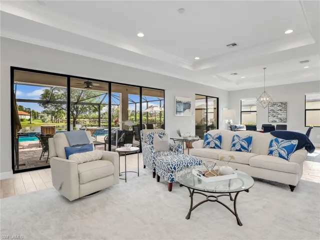 Living room with a raised ceiling, ornamental molding, a sunroom, recessed lighting, and light wood finished floors