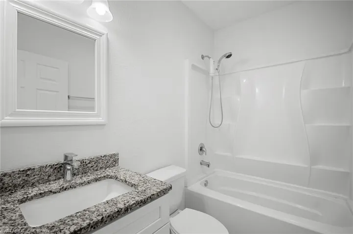 Full bath featuring vanity, shower / bathtub combination, and a textured wall
