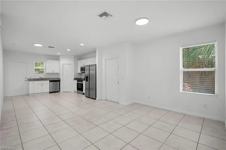 Kitchen featuring white cabinetry, stainless steel appliances, light tile patterned floors, dark countertops, and recessed lighting