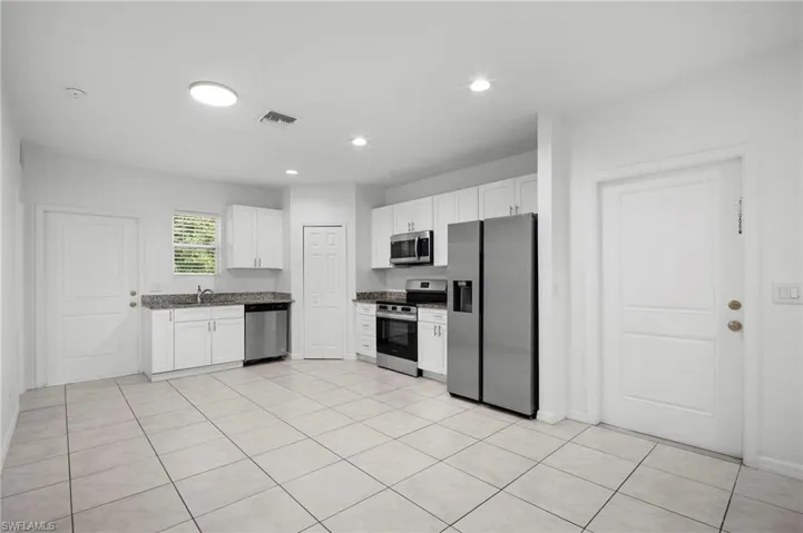 Kitchen featuring stainless steel appliances, white cabinets, light tile patterned floors, and recessed lighting