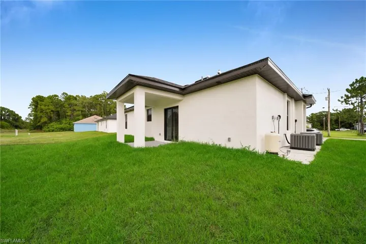 Expansive green lawn with a white stucco exterior and a covered patio area