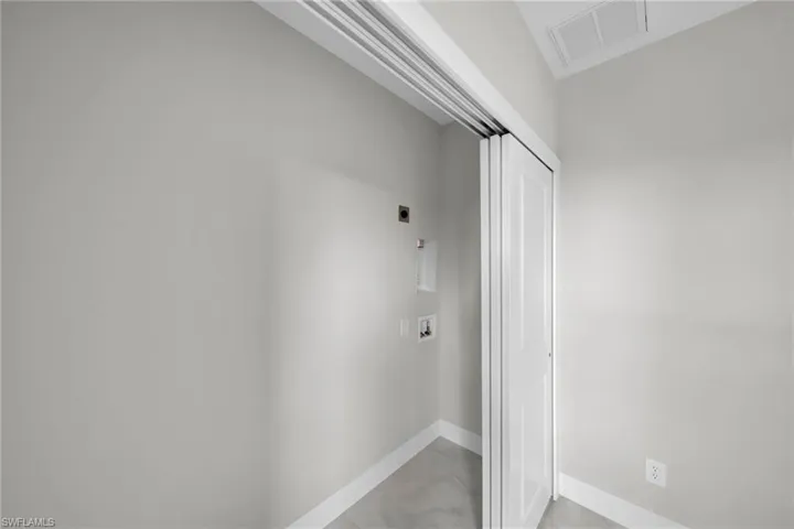 Laundry area featuring a bi-fold door, light gray walls, white baseboards, and tile flooring