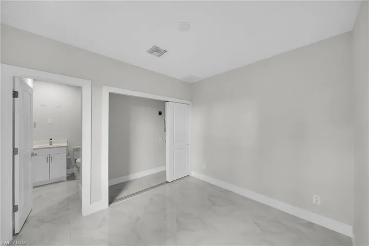 Spacious interior featuring marble-finish tile flooring, neutral wall tones, and white trim
