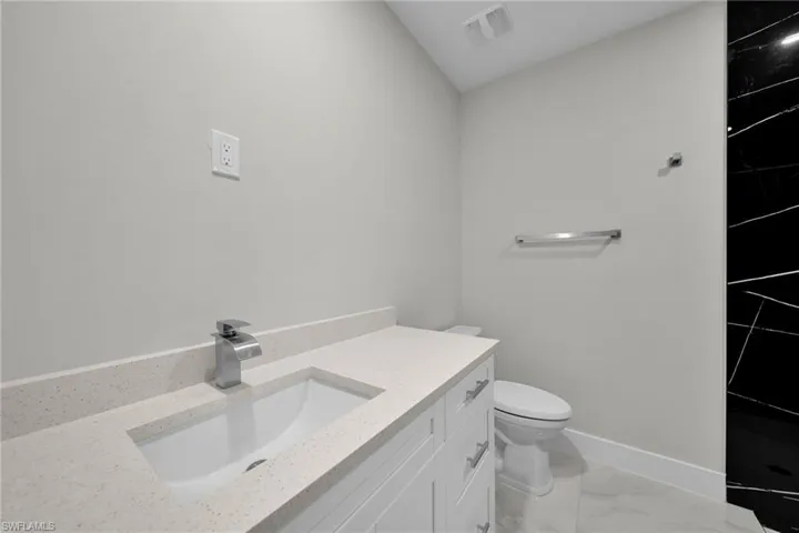 Bathroom vanity featuring a light speckled countertop, undermount sink, and contemporary chrome faucet