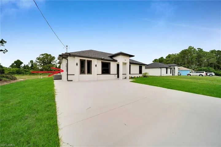 Contemporary residence featuring a light-colored exterior finish, dark trim windows, a dark shingle roof, and an expansive concrete driveway