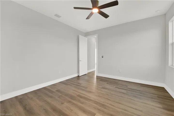 Spare room featuring dark wood-type flooring and ceiling fan