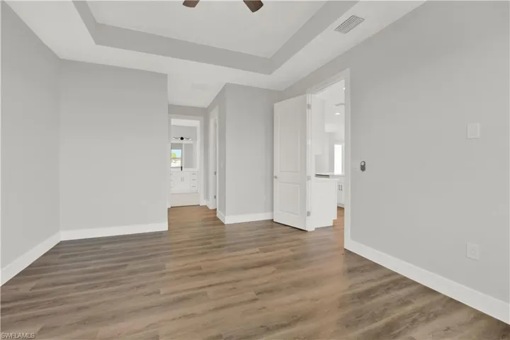 Unfurnished room with a raised ceiling, ceiling fan, and hardwood / wood-style flooring