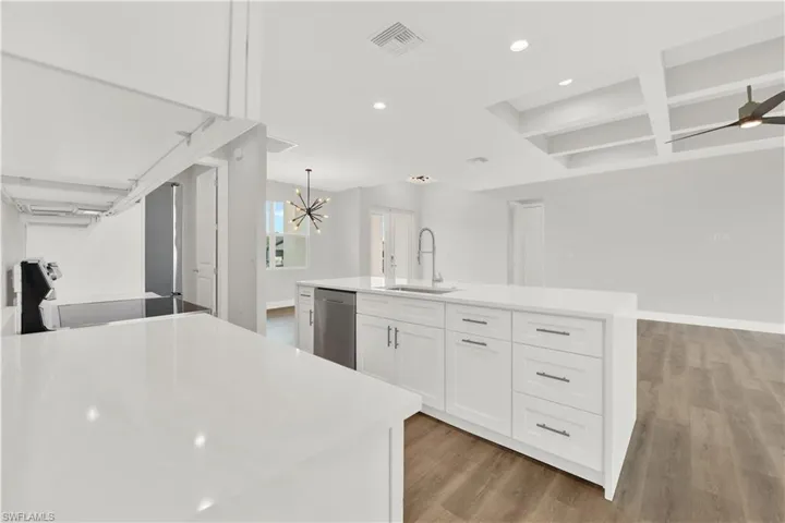 Kitchen with an island with sink, dishwasher, wood-type flooring, range, and sink
