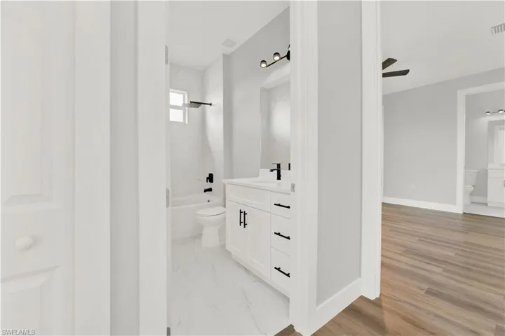 Full bathroom with bathtub / shower combination, vanity, toilet, and wood-type flooring