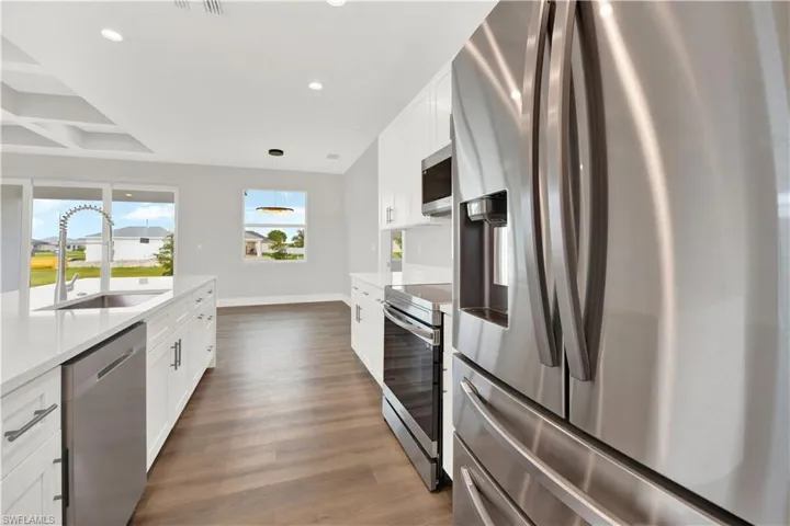 Kitchen featuring stainless steel appliances, sink, dark hardwood / wood-style flooring, and white cabinetry