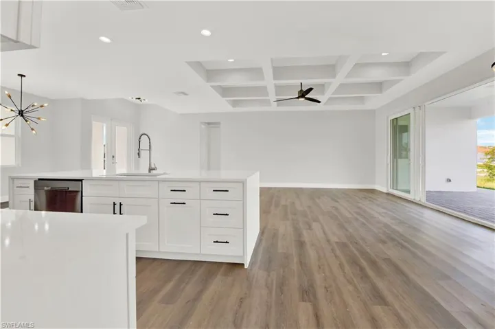 Kitchen featuring coffered ceiling, plenty of natural light, hardwood / wood-style floors, and stainless steel dishwasher