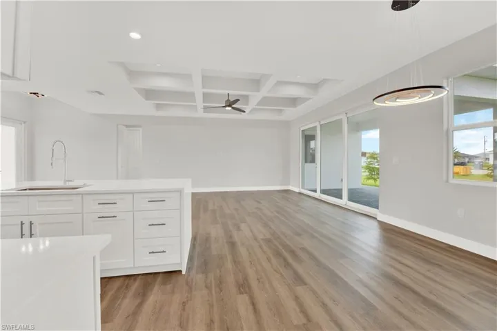 Kitchen featuring white cabinets, hardwood / wood-style flooring, coffered ceiling, and plenty of natural light