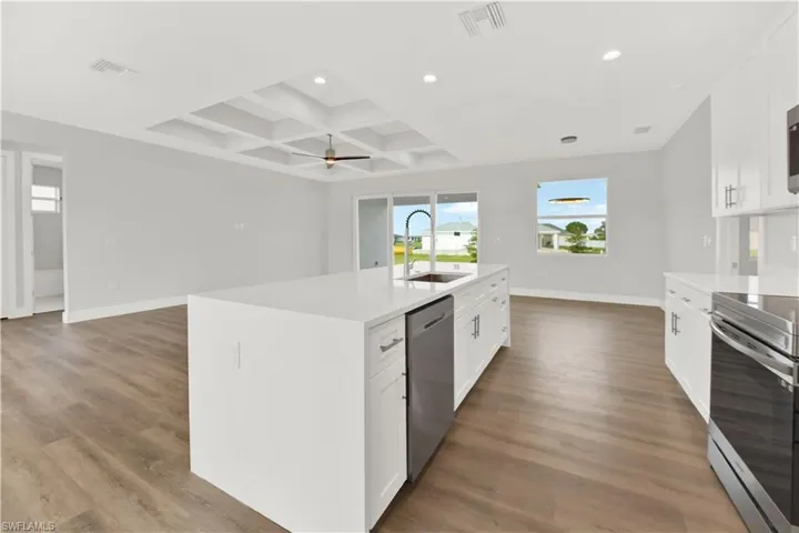 Kitchen featuring dark wood-type flooring, an island with sink, appliances with stainless steel finishes, sink, and coffered ceiling