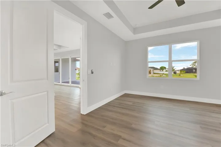 Spare room with a tray ceiling, ceiling fan, and dark hardwood / wood-style floors