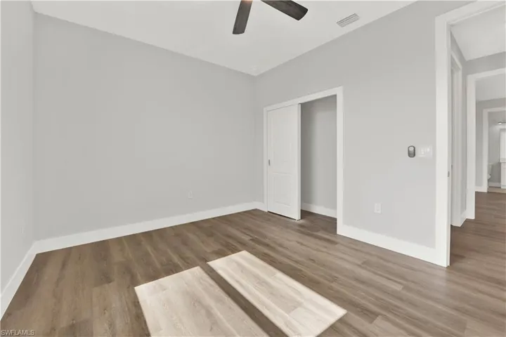 Unfurnished bedroom with ceiling fan, a closet, and wood-type flooring