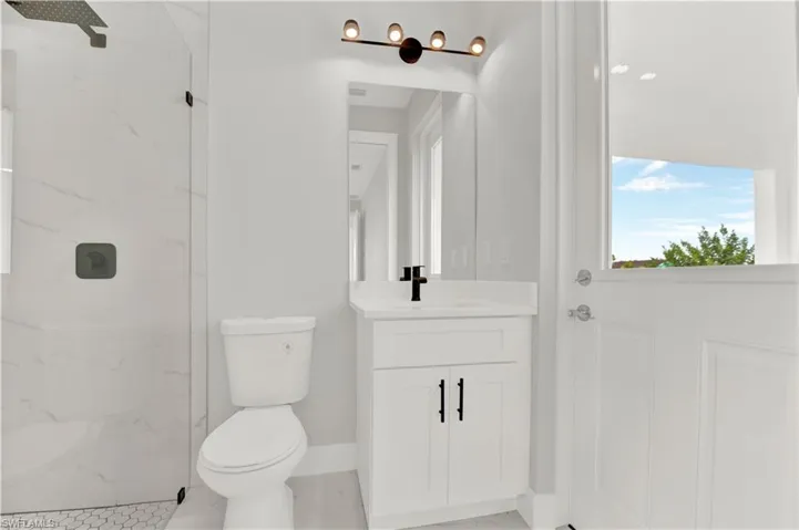 Bathroom with tile floors, tiled shower, toilet, and vanity