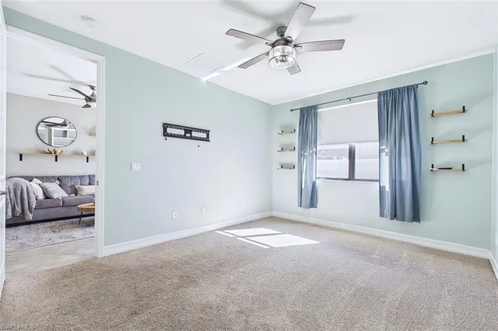 Carpeted empty room featuring ceiling fan and baseboards