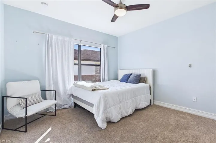 Carpeted bedroom with a ceiling fan and baseboards
