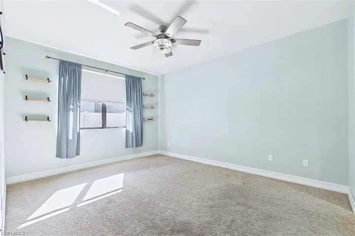Empty room featuring carpet and a ceiling fan