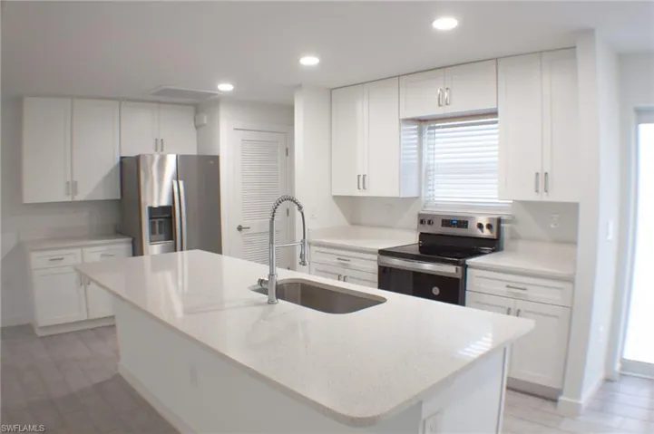 Kitchen featuring a central island with an undermount sink and gooseneck faucet