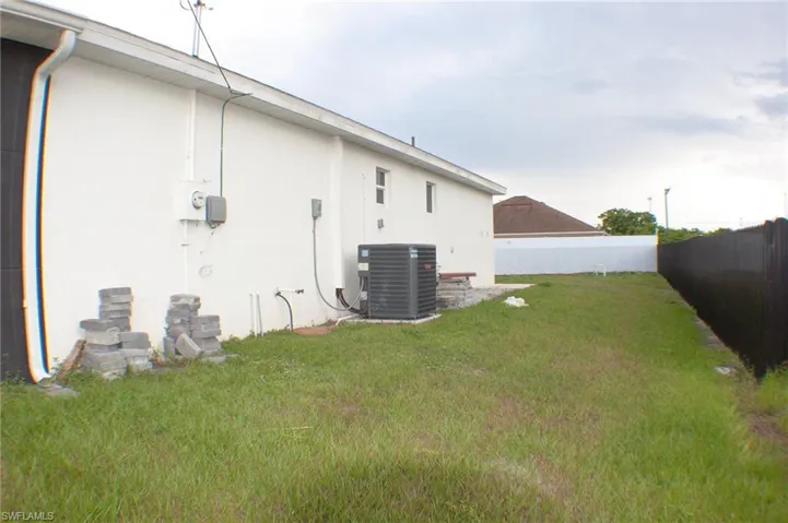 Side yard featuring a stucco exterior, a dark privacy fence, and a grass lawn