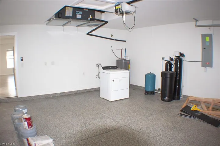 Garage interior featuring a speckled epoxy floor coating, white painted walls, and an overhead HVAC unit