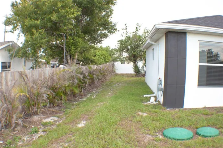 Side yard with natural landscaping bordering a wooden fence