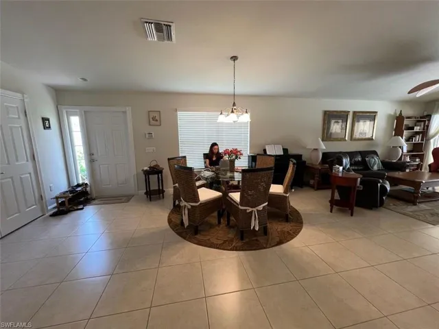 Dining room with light tile patterned flooring and ceiling fan with notable chandelier