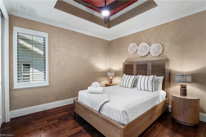 Bedroom featuring crown molding, a raised ceiling, and dark wood finished floors