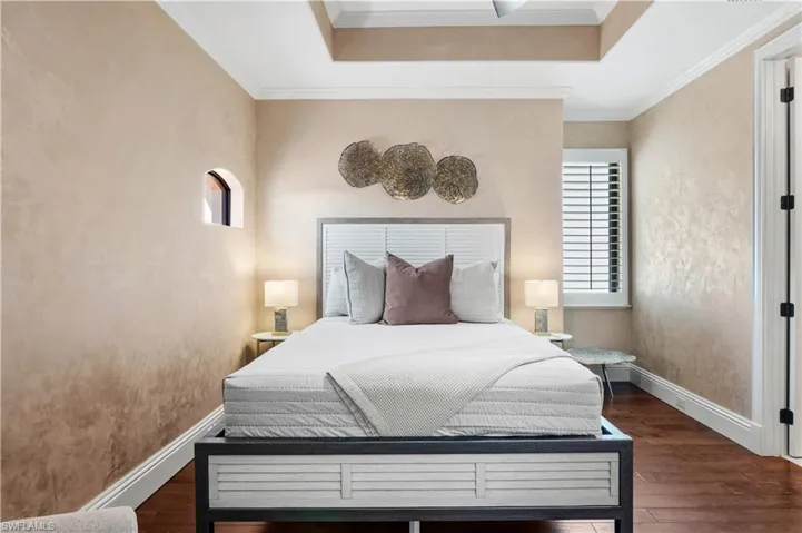 Bedroom featuring dark wood-style flooring, ornamental molding, and a raised ceiling